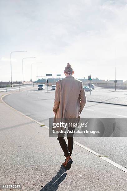full length rear view of young businessman walking on sidewalk - ロングコート ストックフォトと画像