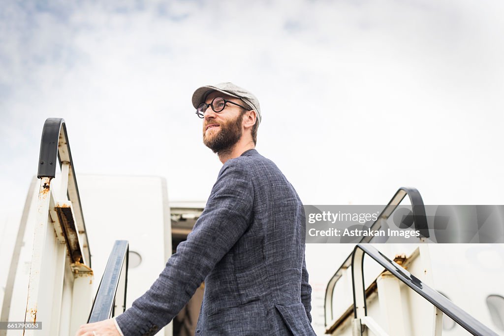Side view of businessman standing on boarding stairs against sky