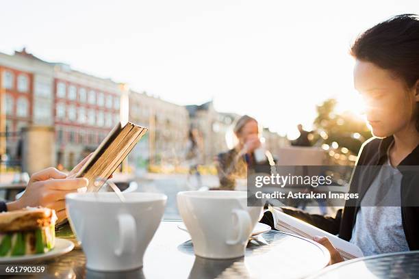 teenagers studying at table in sidewalk cafe - sunlit cafe male stock pictures, royalty-free photos & images