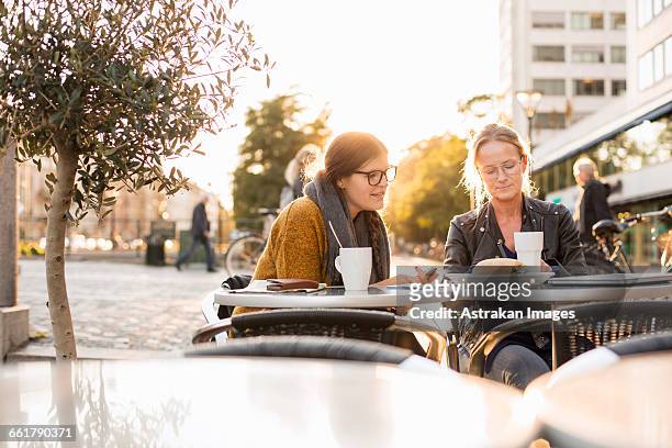businesswomen discussing on table at sidewalk cafe - business meeting cafe stock pictures, royalty-free photos & images