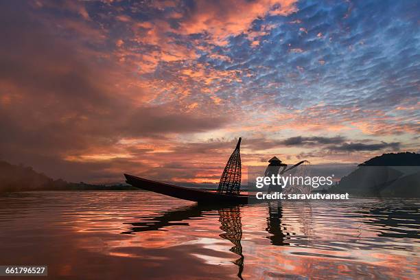 man standing in fishing boat at sunset, mekong river, thailand - river mekong stock pictures, royalty-free photos & images