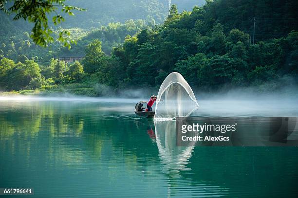 man in boat throwing fishing net, chenzhou, hunan, china - chenzhou stock pictures, royalty-free photos & images
