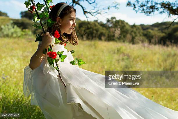 girl wearing first communion  dress sitting on swing in field - comunion fotografías e imágenes de stock