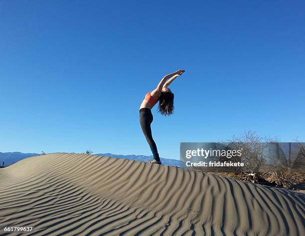 women doing back bend on sand dune, death valley national park, california, america, usa - bending over backwards stock pictures, royalty-free photos & images