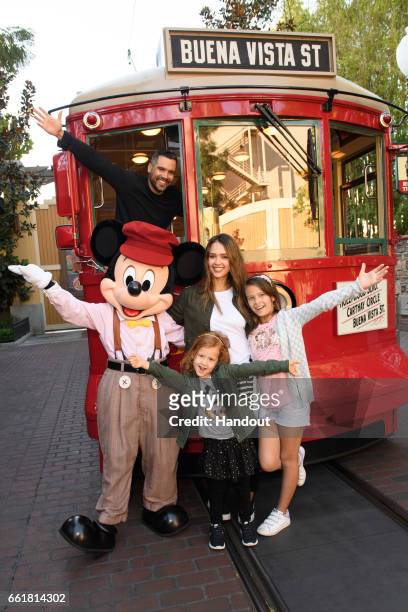 In this handout photo provided by Disney Parks, Actress Jessica Alba, husband Cash Warren and daughters Honor and Haven take a ride with Mickey Mouse...