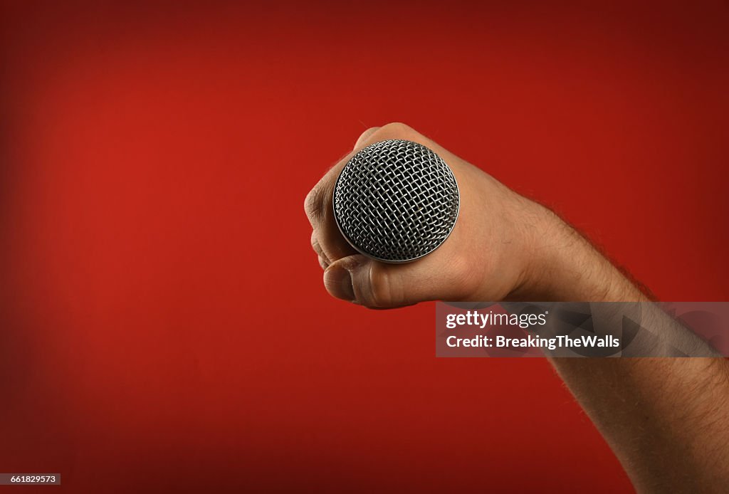 Cropped Image Of Singer Holding Microphone Against Red Background