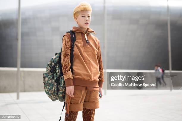 Guest is seen on the street wearing a golden brown velour outfit with camo bag during HERA Seoul Fashion Week on March 30, 2017 in Seoul, South Korea.