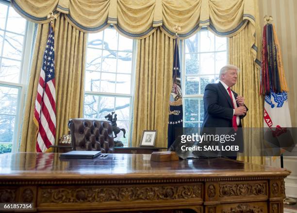 President Donald Trump stands behind the Resolute Desk after speaking about signing executive orders on trade policies in the Oval Office of the...