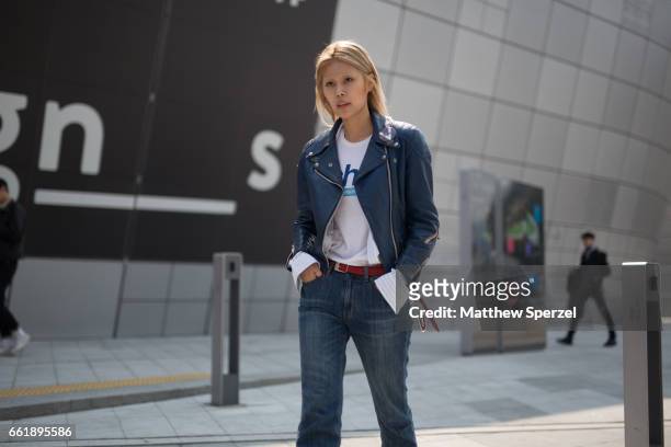 Guest is seen on the street wearing a navy blue leather jacket, white shirt, and blue jeans during HERA Seoul Fashion Week on March 29, 2017 in...