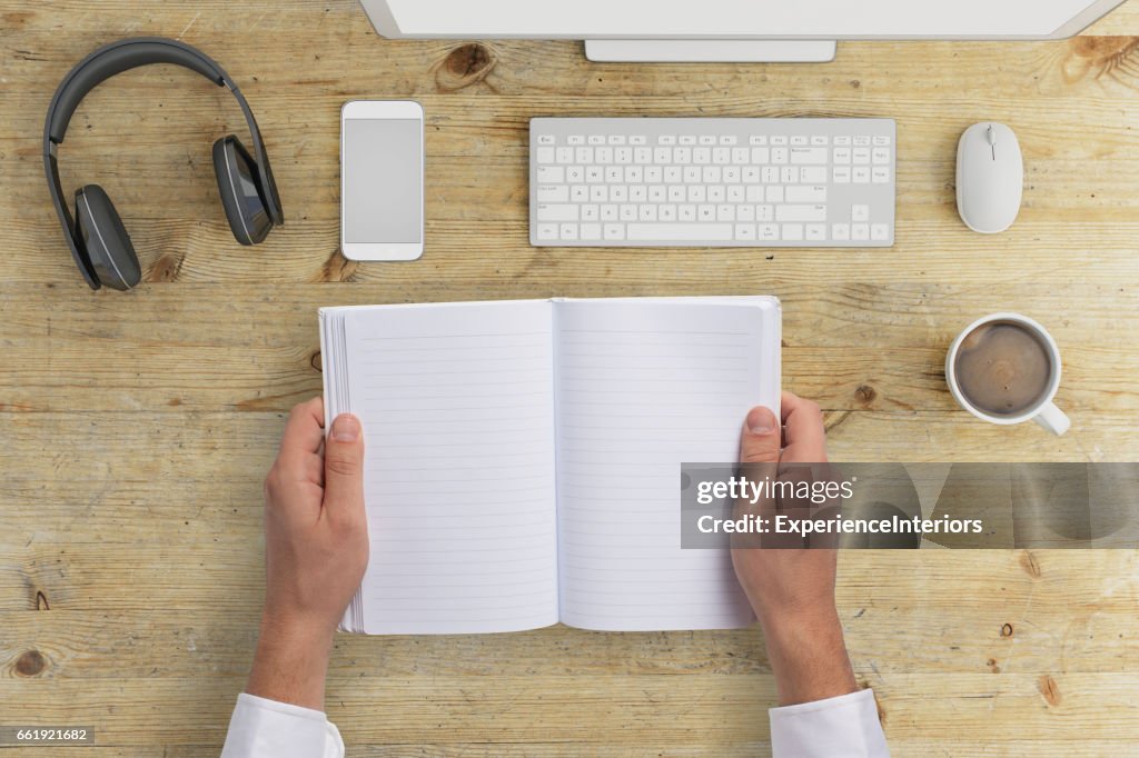 Knolling office desk hands holding notebook