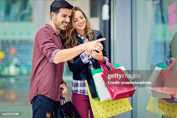 shopping couple is  looking in the store window in the mall - couple shopping in shopping mall stock pictures, royalty-free photos & images