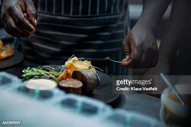 close-up of chef finishing dish in kitchen - kochen nahaufnahme stock-fotos und bilder