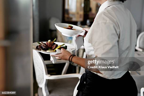 waiter walking with dishes inside restaurant - kellner oder kellnerin stock-fotos und bilder