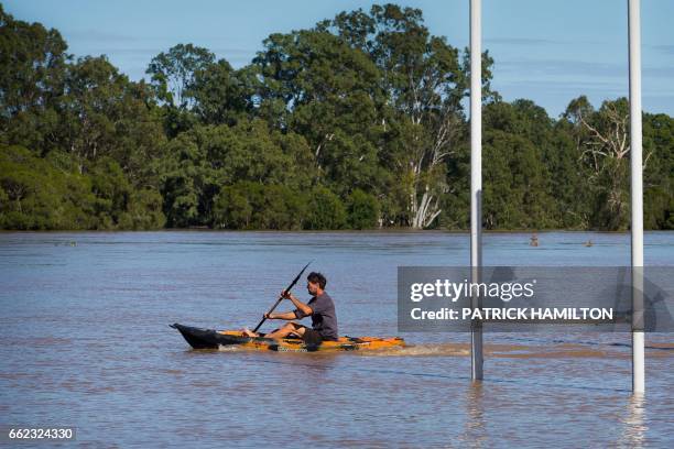 Resident uses a kayak to paddle past goal posts, partially submerged under floodwaters caused by Cyclone Debbie, to rescue a stranded cow on his...