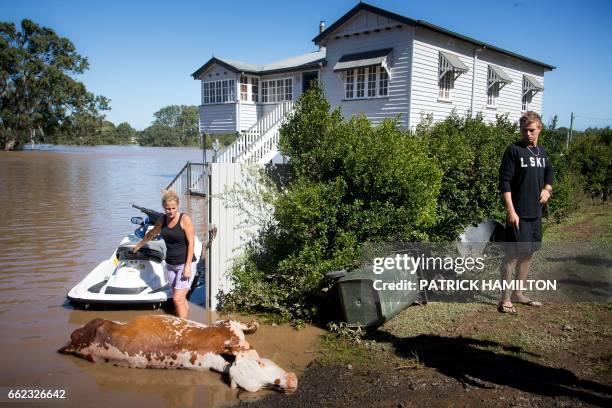 Residents look at a cow, which drowned in floodwaters caused by Cyclone Debbie, that they recovered on their property in North MacLean, Brisbane on...