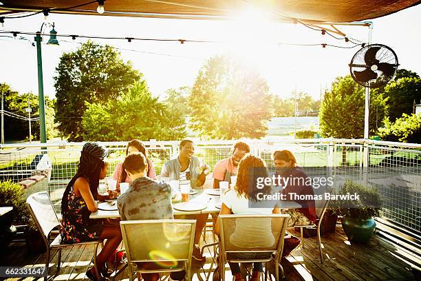 friends sharing drinks at table on restaurant deck - patio restaurant stock pictures, royalty-free photos & images