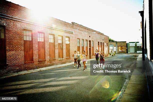 group of women running together on urban street - five friends unity stock pictures, royalty-free photos & images