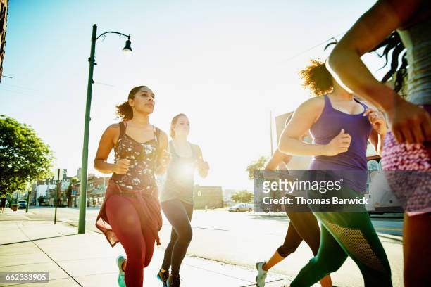 group of women running on sidewalk at sunrise - five friends unity stock pictures, royalty-free photos & images