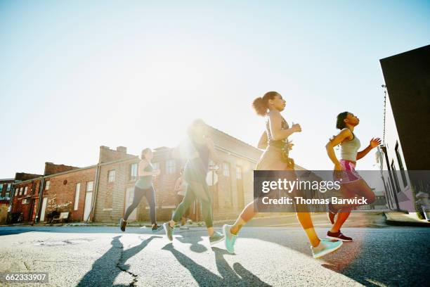 group of women running together at sunrise - running shoes sky ストックフォトと画像