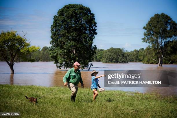 Property owner Tom Archibald walks with his son Blaze and dog Shadow on the flooded banks of the Logan River caused by Cyclone Debbie, in North...