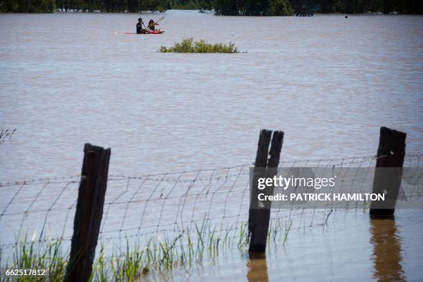 Kayakers paddle on the flooded Logan River, caused by Cyclone Debbie, as it flows over the Mt Lindesay Highway in Waterford West near Brisbane on...