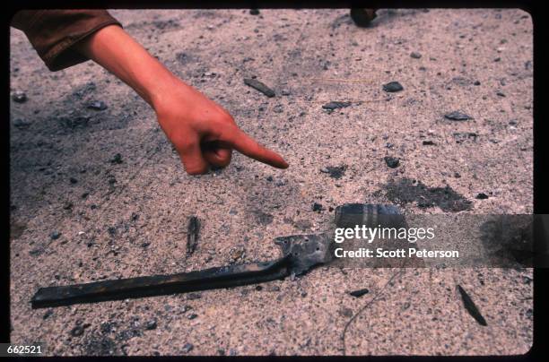 Kosovar points to a shell casing containing radiocative contaminated waste, August 28,1999 Djakovica, Kosovo, Yugoslavia. The western side of...