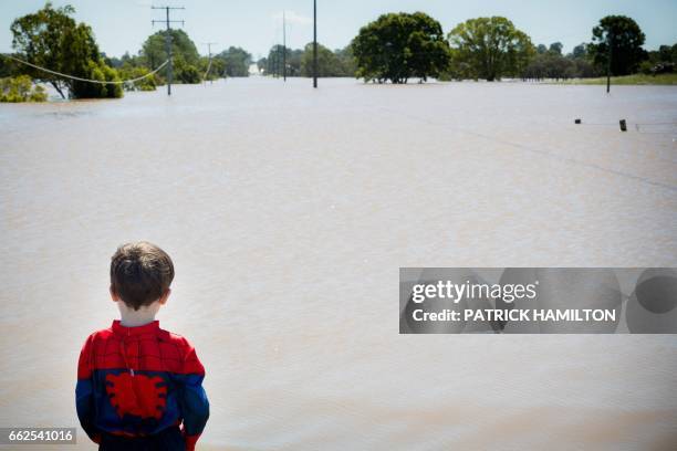 Seth Skirving watches floodwaters of the Logan River, caused by Cyclone Debbie, flow over the Mt Lindesay Highway in Waterford West near Brisbane on...