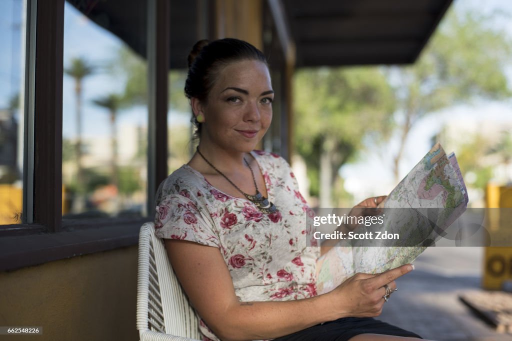 Woman sitting outside cafe holding map