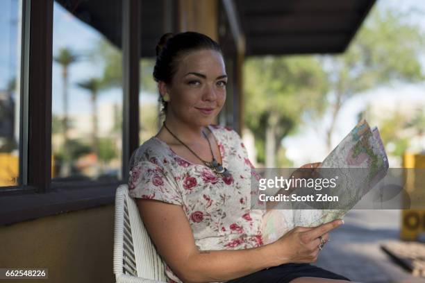 woman sitting outside cafe holding map - scott zdon foto e immagini stock