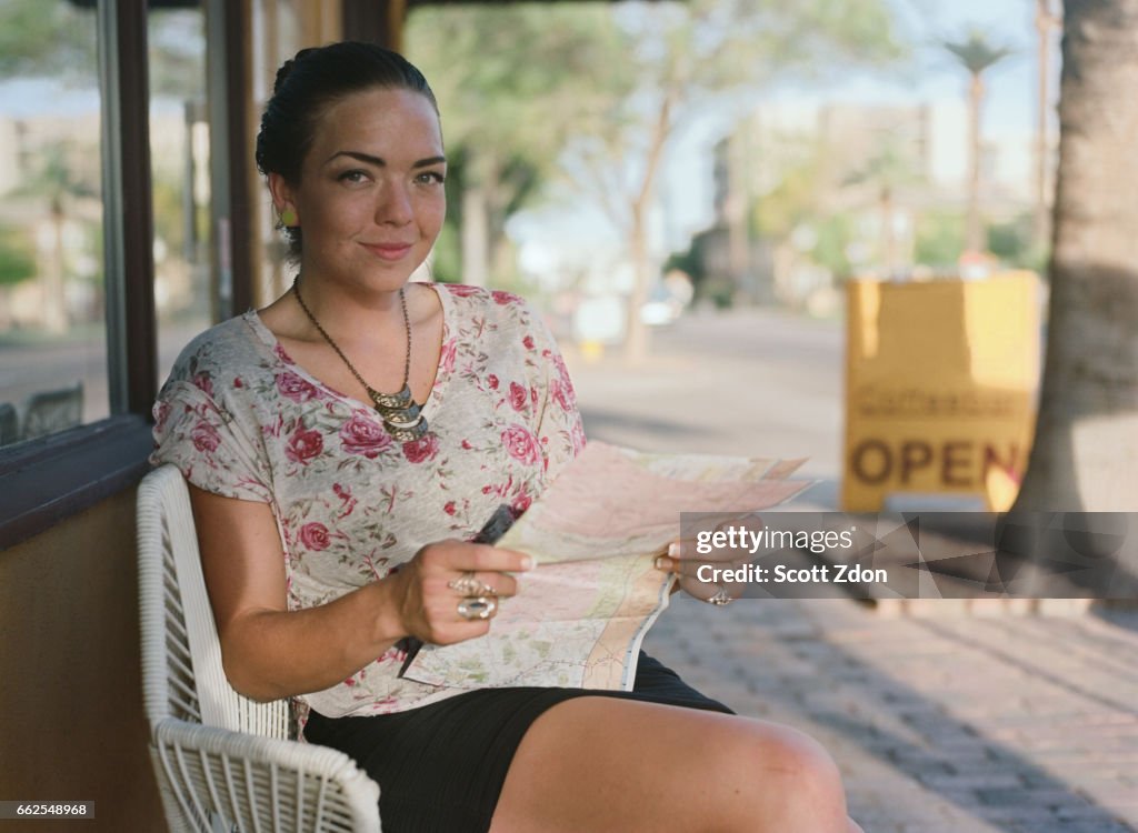 Woman sitting outside cafe holding map