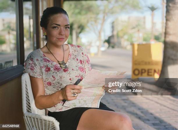 woman sitting outside cafe holding map - scott zdon bildbanksfoton och bilder