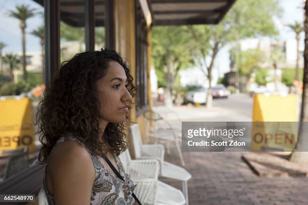 side view of woman sitting outside neighborhood cafe - scott zdon stock-fotos und bilder