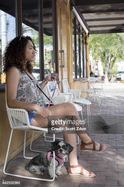 side view of woman sitting outside cafe with dog - scott zdon fotografías e imágenes de stock
