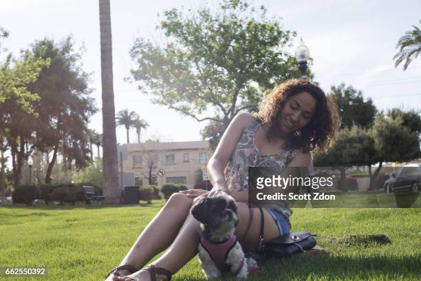 woman sitting in park with dog - scott zdon stock-fotos und bilder