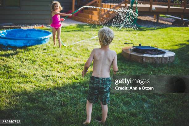 little girl waving a garden hose - annie sprinkle stock pictures, royalty-free photos & images