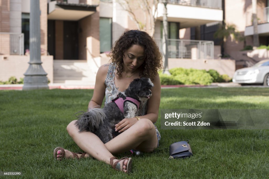 Woman sitting in park with dog on her lap