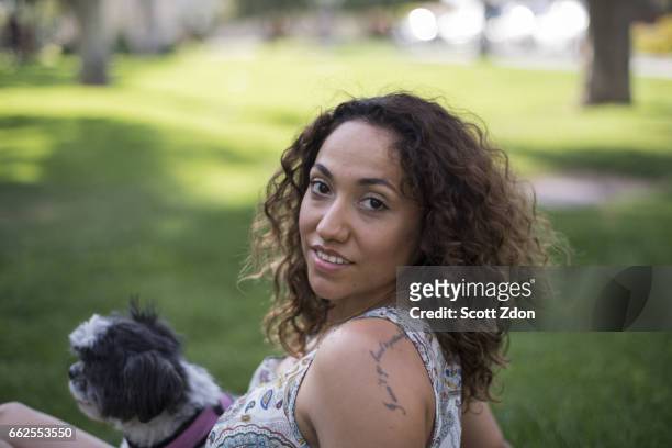 woman sitting in park with dog on her lap - scott zdon foto e immagini stock