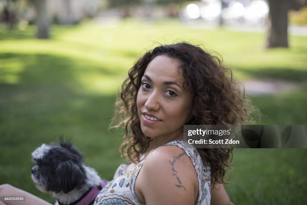 Woman sitting in park with dog on her lap