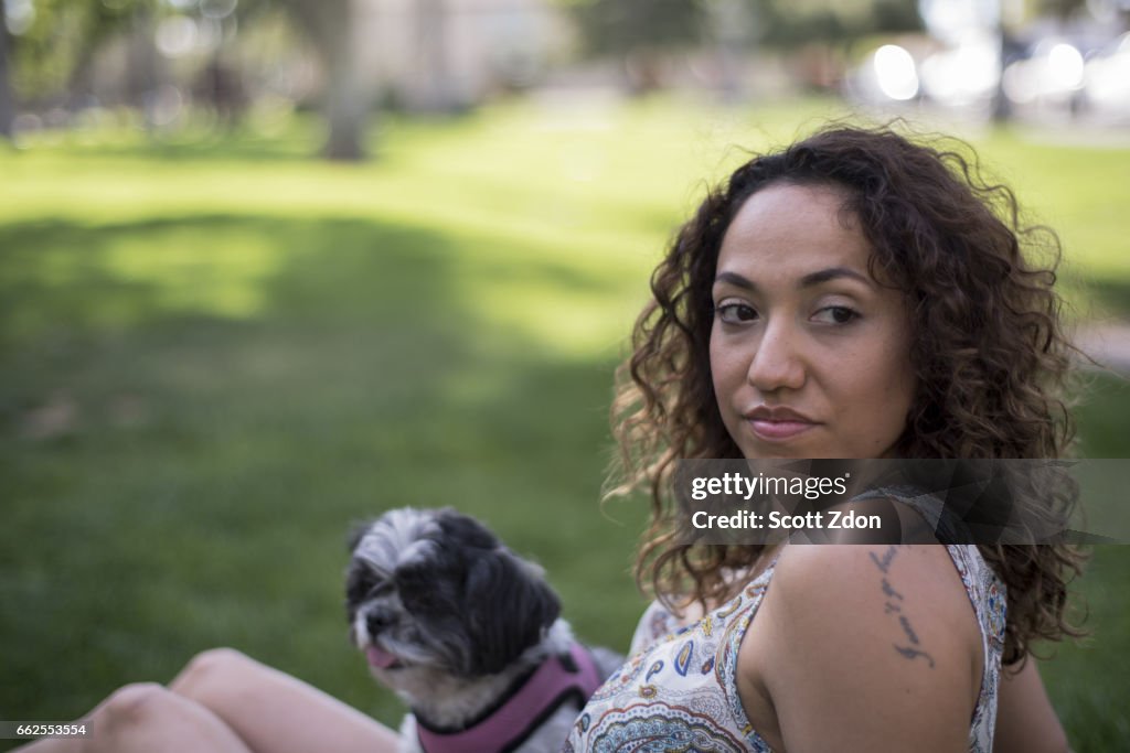Woman sitting in park with dog on her lap