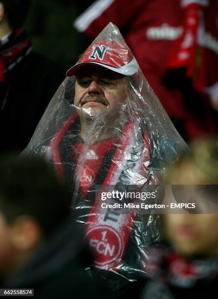 An FC Nurnberg fan improvises a rain cover the stands