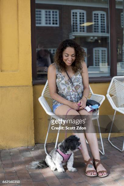 woman sitting outside cafe with dog - scott zdon stock-fotos und bilder