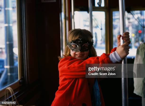 young girl on new orleans streetcar wearing mardi gras mask - scott zdon stock-fotos und bilder