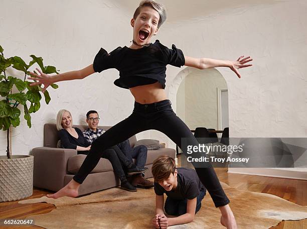 young girl jumping over brother. - legs spread - fotografias e filmes do acervo