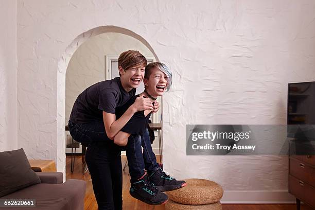 young girl giving boy a piggyback ride. - troy bond stock pictures, royalty-free photos & images