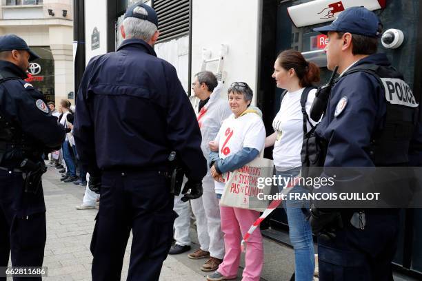 Police officers surround activists from the Association for the Taxation of financial Transactions and Citizen's Action after they painted in white...