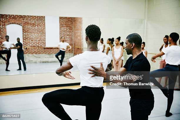 Ballet instructor adjusting students form