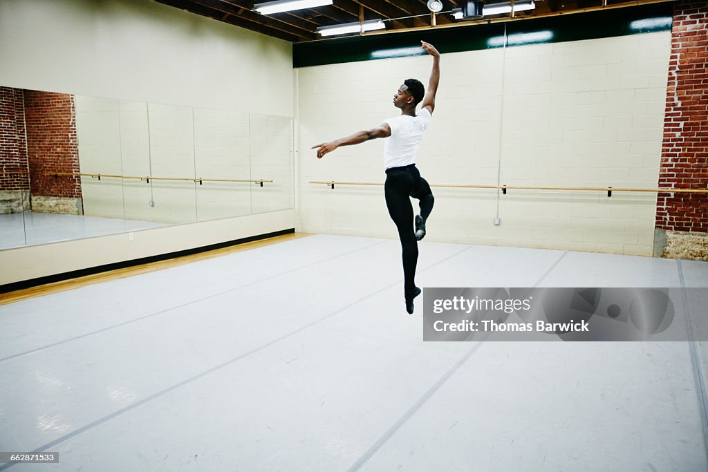 Male ballet dancer leaping in air during practice