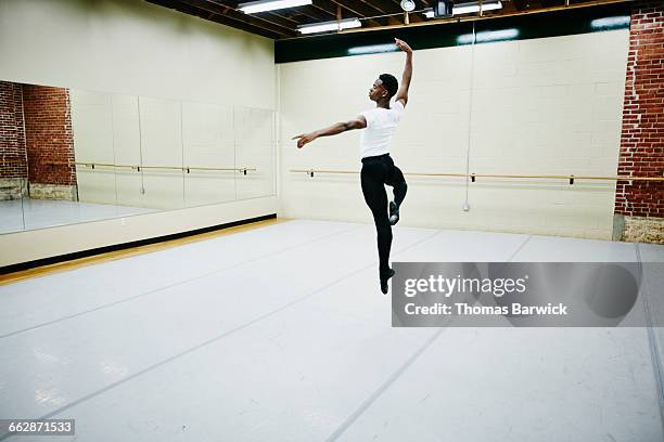 male ballet dancer leaping in air during practice - ballet boy foto e immagini stock