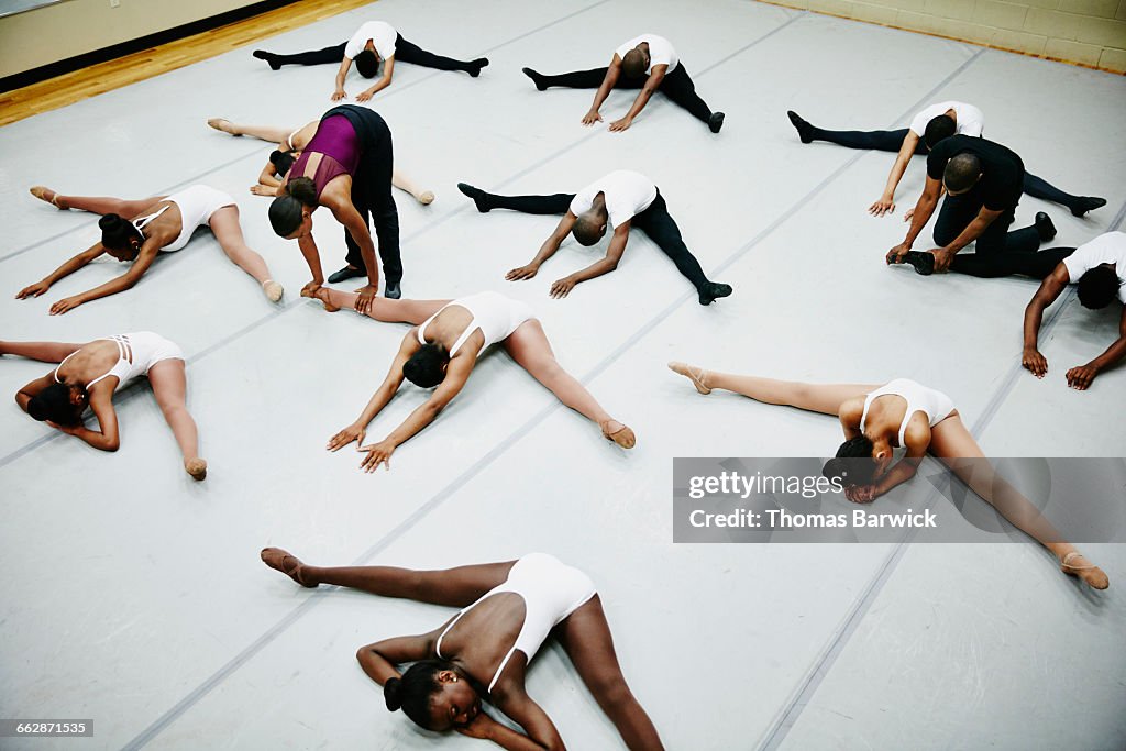 Ballet instructors assisting students stretching