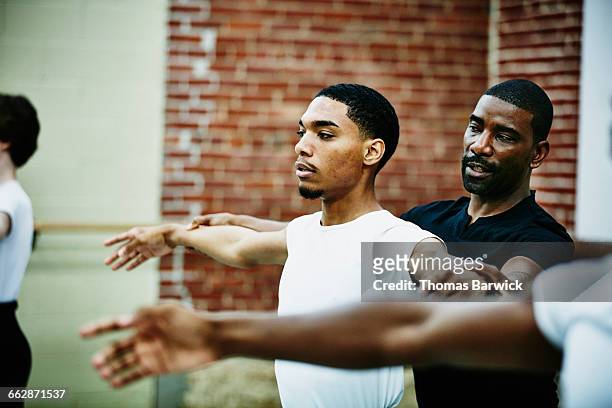 Male ballet instructor adjusting students form